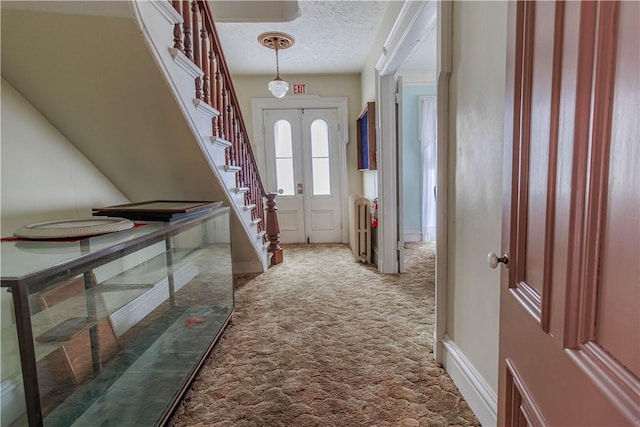 carpeted foyer with a textured ceiling