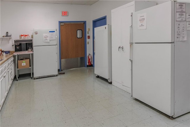 kitchen with white refrigerator and white cabinetry