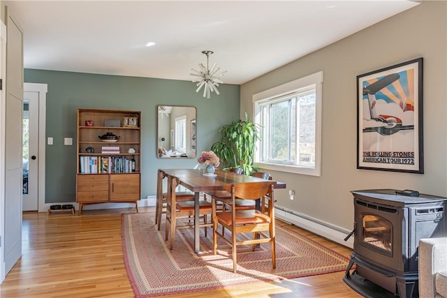 dining space featuring a chandelier, light hardwood / wood-style floors, a wood stove, and baseboard heating