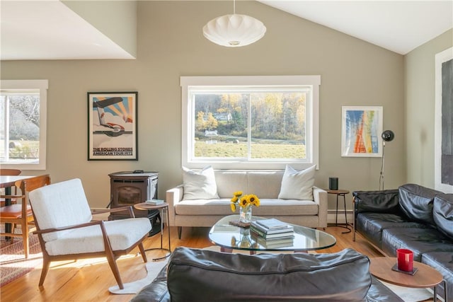 living room with hardwood / wood-style flooring, a wood stove, a wealth of natural light, and vaulted ceiling