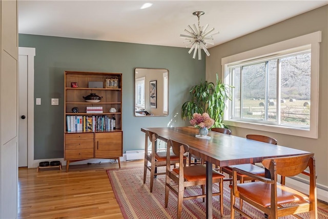 dining space featuring light wood-type flooring and an inviting chandelier