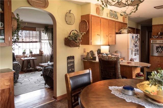 dining room featuring wood finished floors and arched walkways