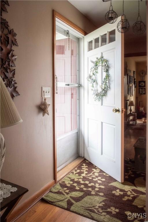 doorway to outside featuring baseboards and wood finished floors
