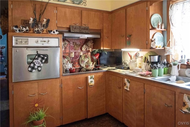 kitchen with light countertops, stainless steel oven, under cabinet range hood, black electric stovetop, and brown cabinetry