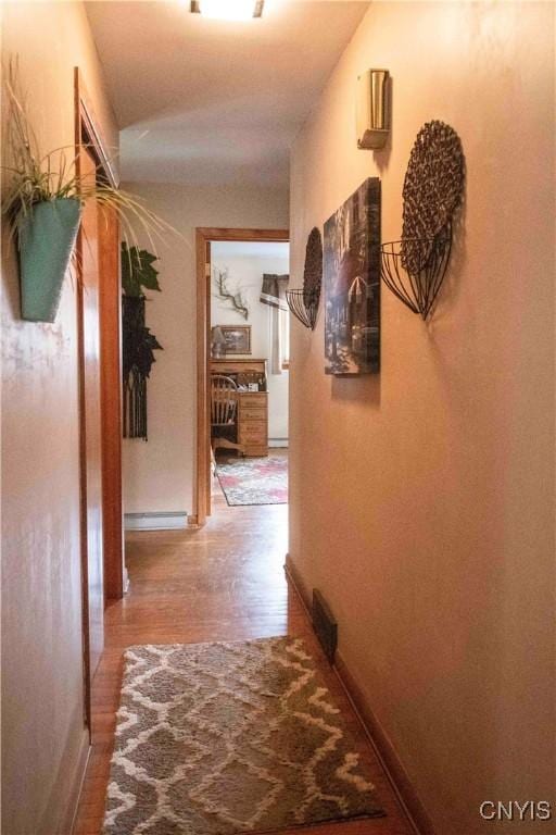 corridor with baseboards and wood finished floors
