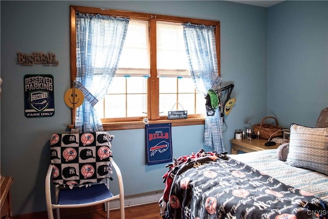 bedroom featuring a baseboard heating unit and wood finished floors