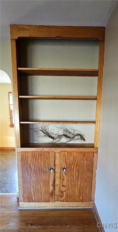 room details with arched walkways, baseboards, wood finished floors, and built in features