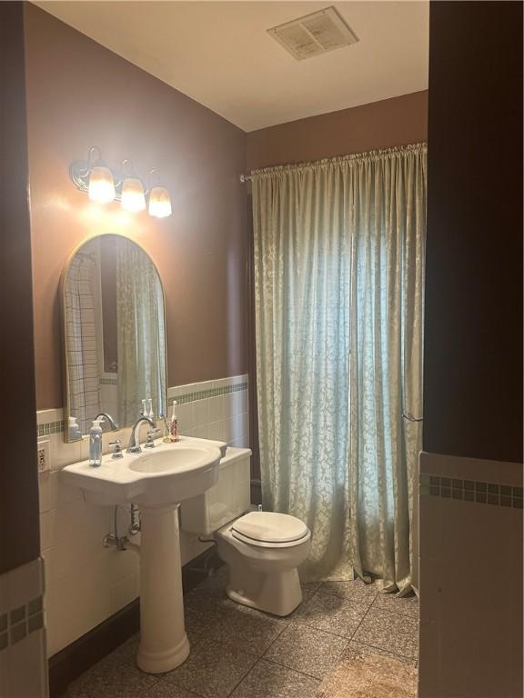 bathroom featuring toilet and tile walls