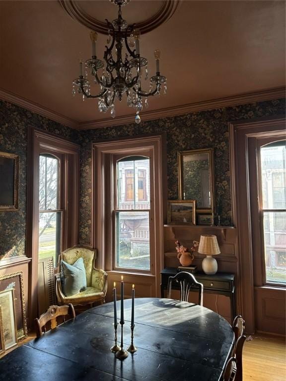 dining room featuring ornamental molding, light wood-type flooring, and an inviting chandelier