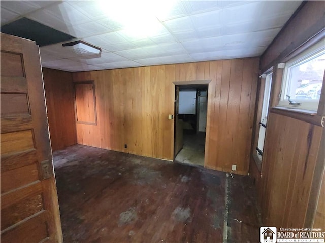 unfurnished room featuring wooden walls