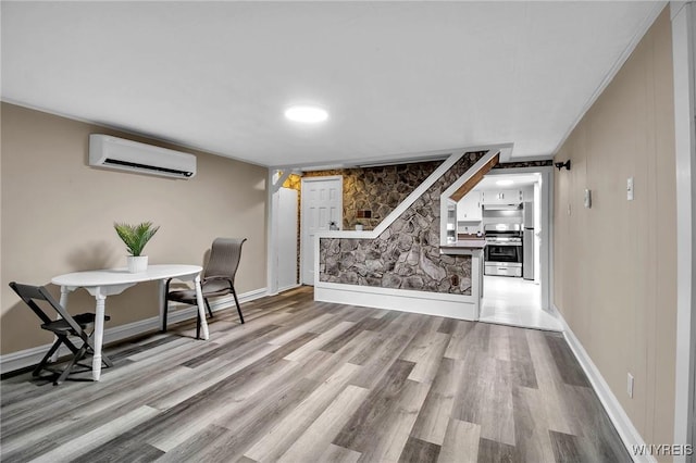 interior space with baseboards, a wall unit AC, and wood finished floors