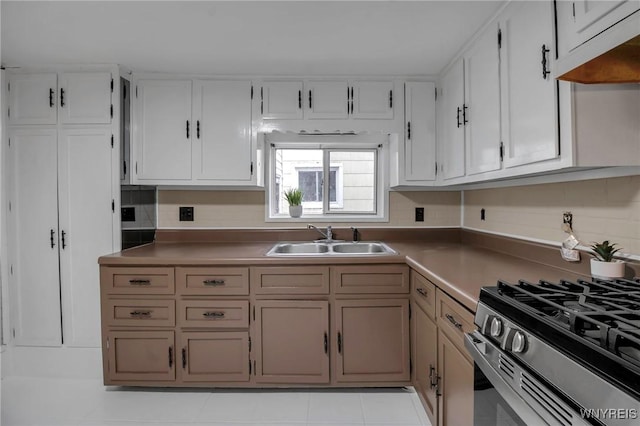 kitchen with decorative backsplash, under cabinet range hood, stainless steel gas range, and a sink