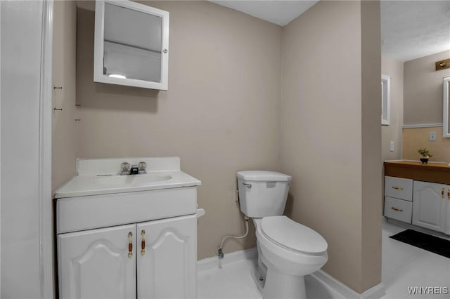 half bath with vanity, toilet, and baseboards