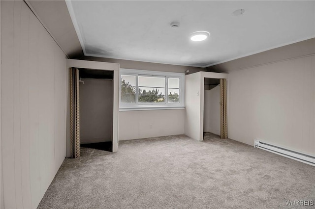 unfurnished bedroom with carpet flooring, lofted ceiling, a baseboard heating unit, and multiple closets