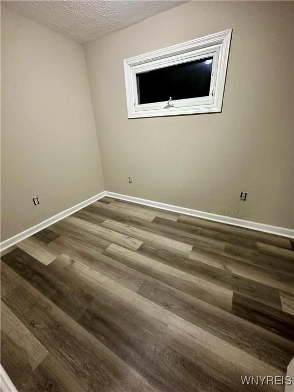 empty room with dark wood-style floors, baseboards, and a textured ceiling