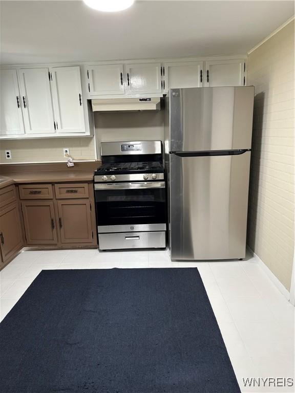 580 S Ogden St, Buffalo, NY 14206 - kitchen with appliances with stainless steel finishes, under cabinet range hood, dark countertops, light tile patterned floors, and white cabinets