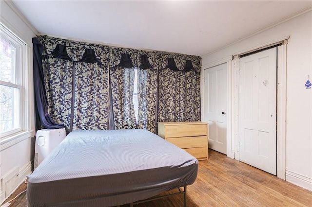 bedroom with wood-type flooring, multiple windows, and crown molding