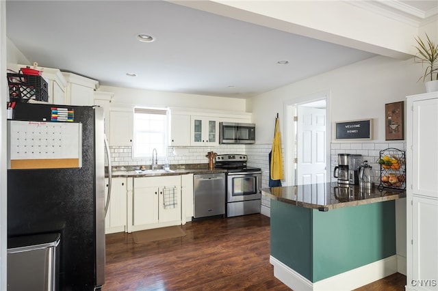 kitchen with sink, appliances with stainless steel finishes, white cabinetry, dark hardwood / wood-style flooring, and kitchen peninsula