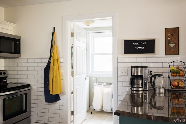 kitchen featuring light tile patterned floors, stainless steel appliances, and tile walls