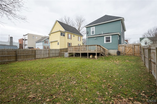 rear view of house with a wooden deck and a lawn