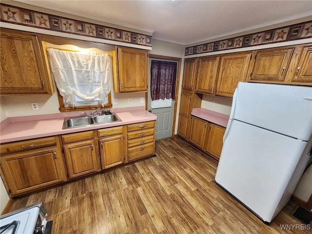 kitchen featuring sink, crown molding, white fridge, light wood-type flooring, and range