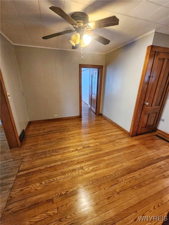 unfurnished room featuring ceiling fan, light wood-type flooring, and crown molding