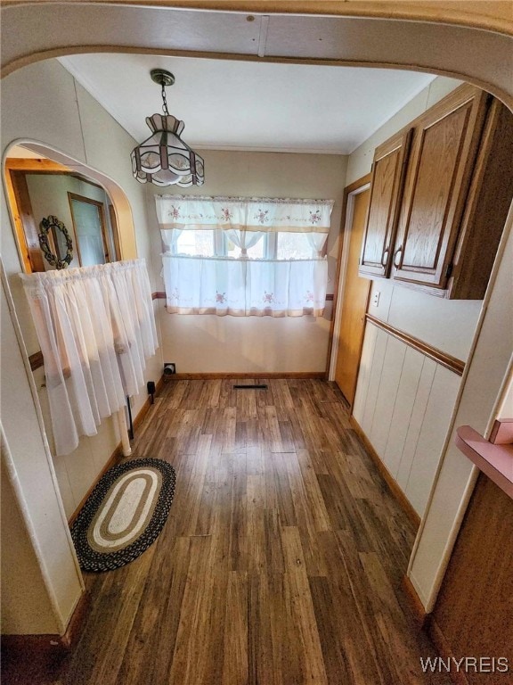 unfurnished dining area featuring dark wood-type flooring and a notable chandelier