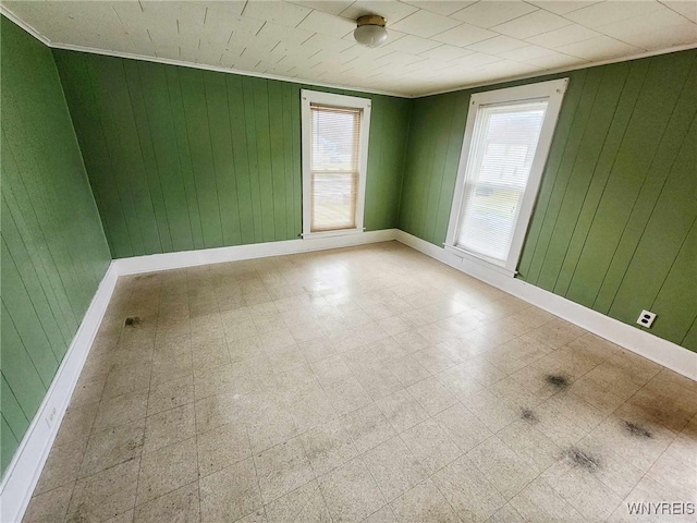 spare room featuring crown molding and wood walls