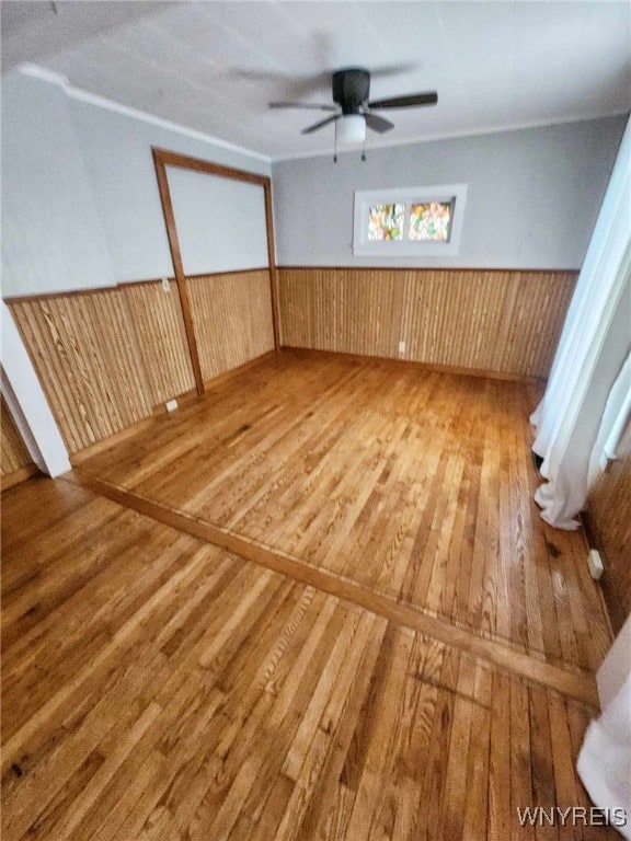 unfurnished room featuring wood-type flooring, ceiling fan, and wood walls