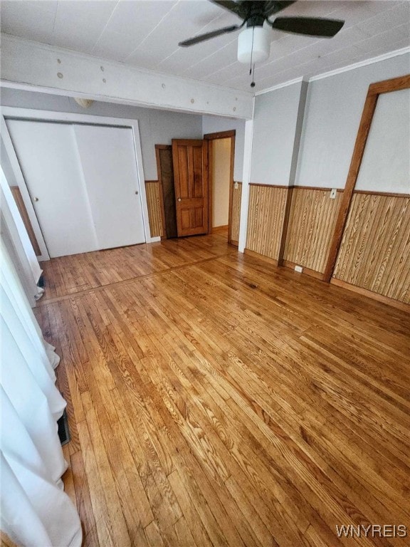 unfurnished bedroom featuring wood-type flooring, ceiling fan, and wood walls