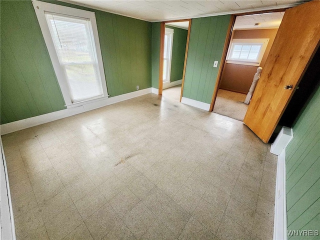 unfurnished room featuring a wealth of natural light and wooden walls