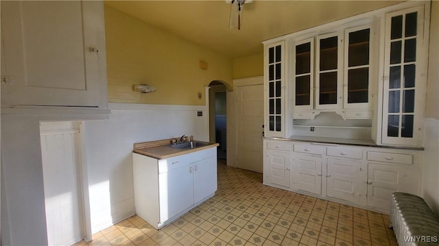 kitchen with white cabinetry, sink, and lofted ceiling