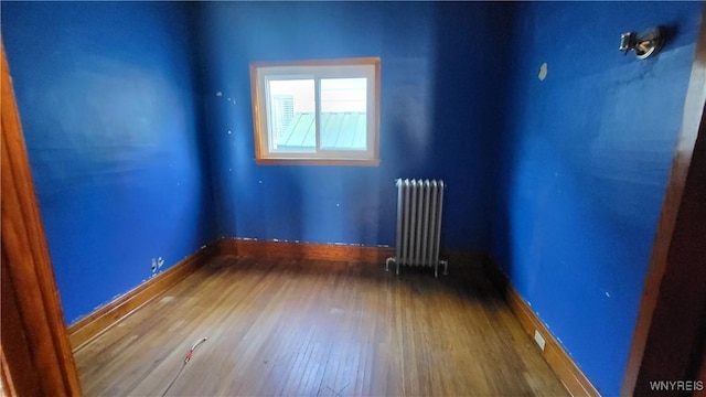 unfurnished room featuring hardwood / wood-style floors and radiator