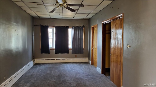 empty room featuring a paneled ceiling, ceiling fan, and a baseboard heating unit