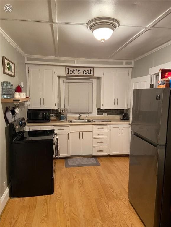 kitchen featuring light wood-type flooring, tasteful backsplash, sink, black appliances, and white cabinets