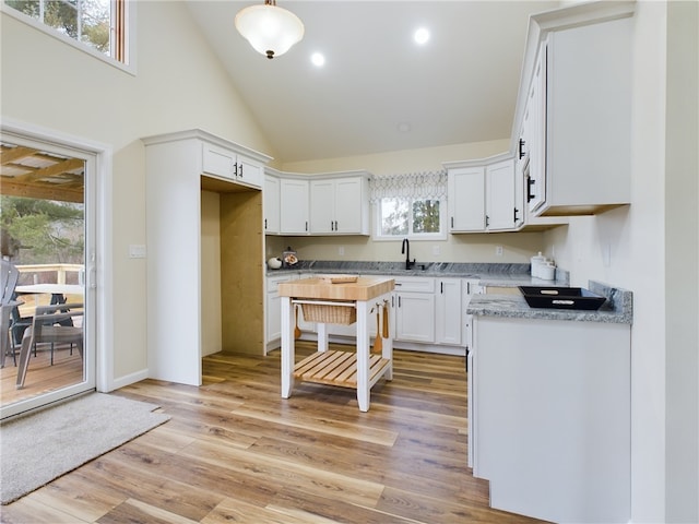 kitchen featuring white cabinets, high vaulted ceiling, light hardwood / wood-style flooring, and a wealth of natural light