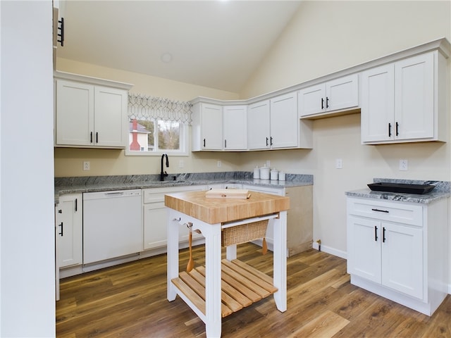 kitchen with light stone countertops, white dishwasher, wood-type flooring, vaulted ceiling, and white cabinets