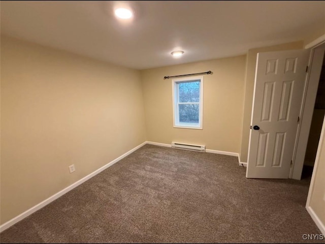 carpeted spare room featuring a baseboard heating unit