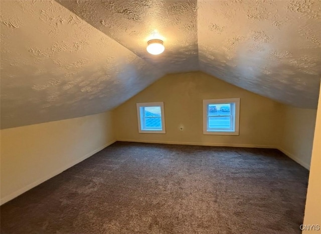 bonus room featuring dark colored carpet, a textured ceiling, and vaulted ceiling