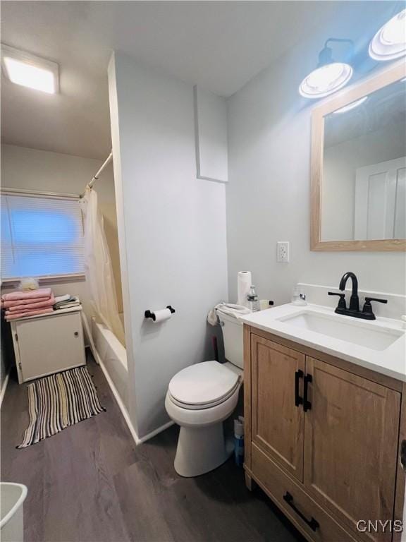 full bathroom with shower / bath combo with shower curtain, hardwood / wood-style floors, vanity, and toilet