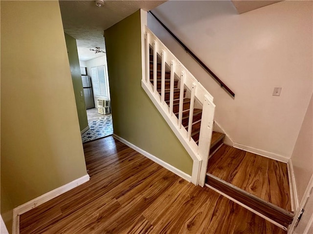 staircase with wood-type flooring and a textured ceiling