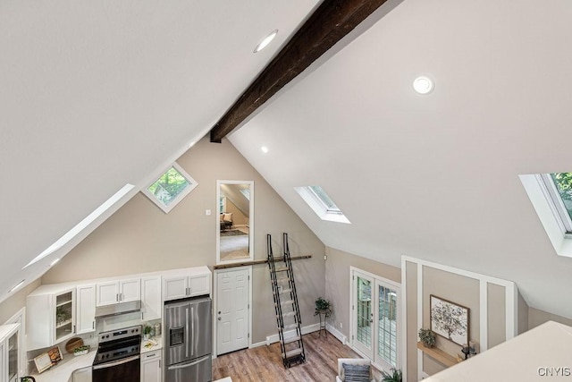 interior space with lofted ceiling with skylight, light hardwood / wood-style flooring, white cabinets, and appliances with stainless steel finishes