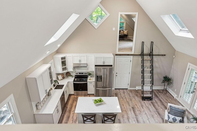 living room with light hardwood / wood-style flooring, high vaulted ceiling, plenty of natural light, and sink