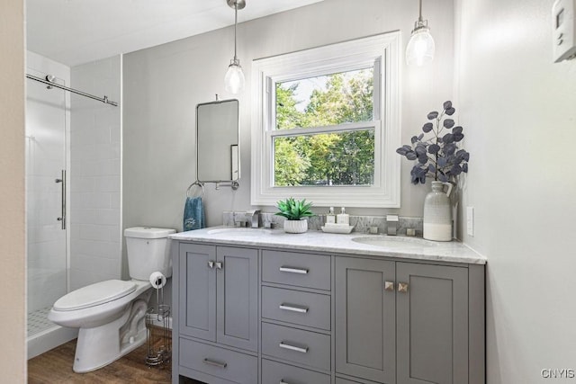 bathroom with vanity, toilet, wood-type flooring, and tiled shower