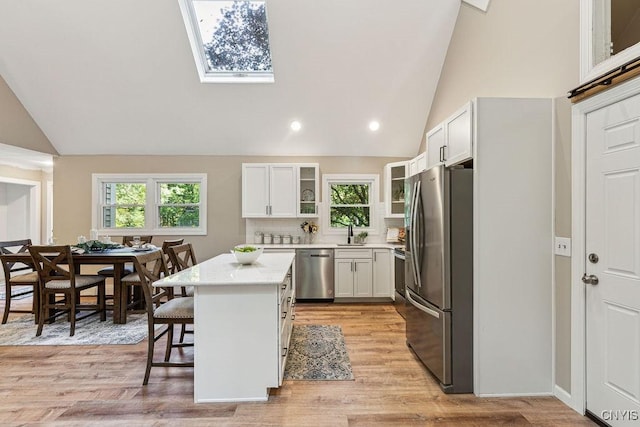 kitchen featuring decorative backsplash, appliances with stainless steel finishes, a breakfast bar, white cabinets, and a kitchen island