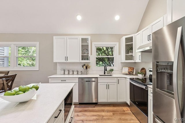 kitchen with tasteful backsplash, stainless steel appliances, vaulted ceiling, sink, and white cabinets