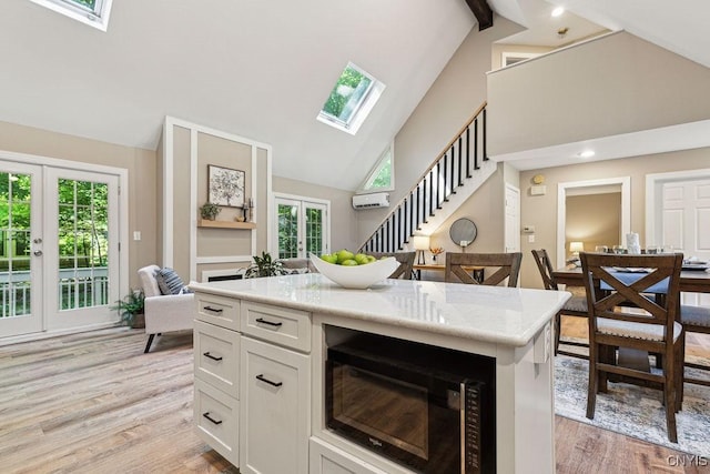 kitchen featuring french doors, light wood-type flooring, beamed ceiling, white cabinetry, and black microwave