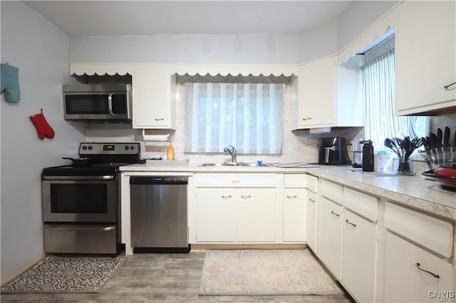 kitchen featuring white cabinets, sink, appliances with stainless steel finishes, and light hardwood / wood-style flooring