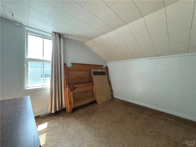 bonus room featuring plenty of natural light, vaulted ceiling, and dark colored carpet