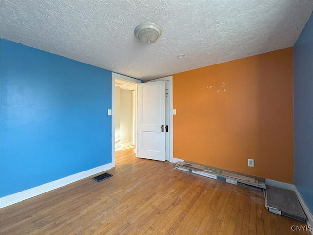 empty room with a textured ceiling and light hardwood / wood-style floors